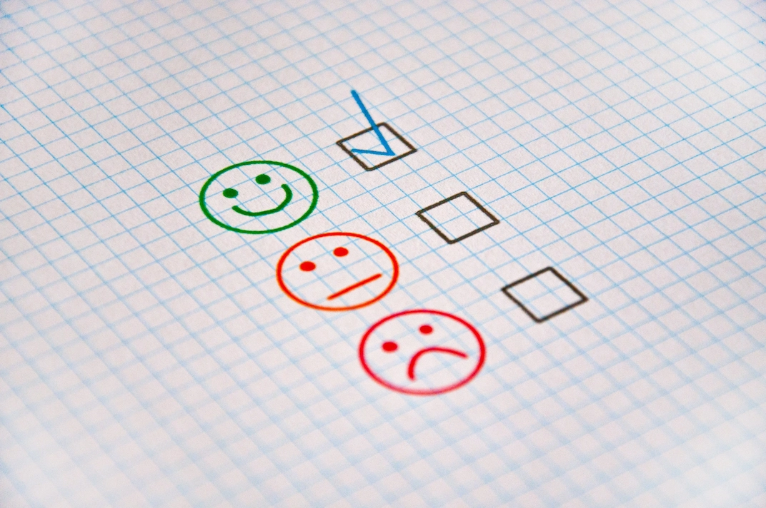 Client donnant son avis de satisfaction avec des icônes de satisfaction positive, neutre et négative sur un questionnaire.