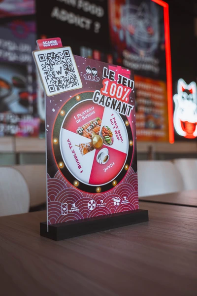 Chevalet du jeu 100% gagnant Godo Sushi avec QR code posé sur une table du restaurant