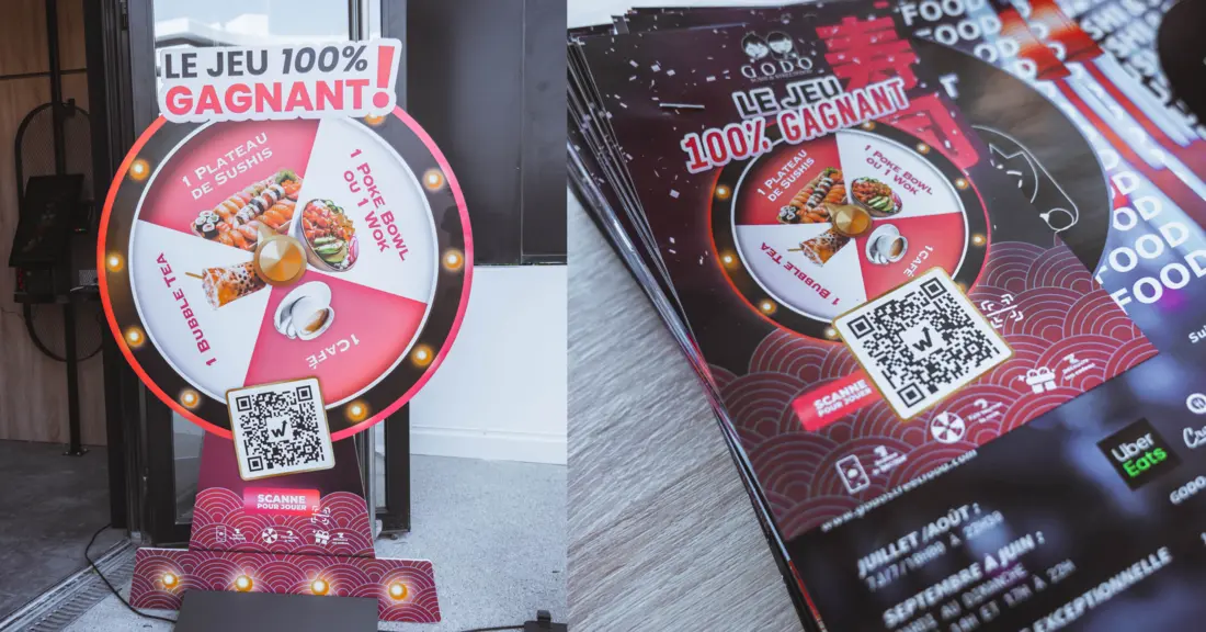 Roue à cadeaux grandeur nature à l'entrée de Godo Sushi et pile de flyers du jeu concours