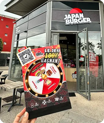 Flyer du jeu 100% gagnant avec QR code brandi devant la façade de Japan Burger