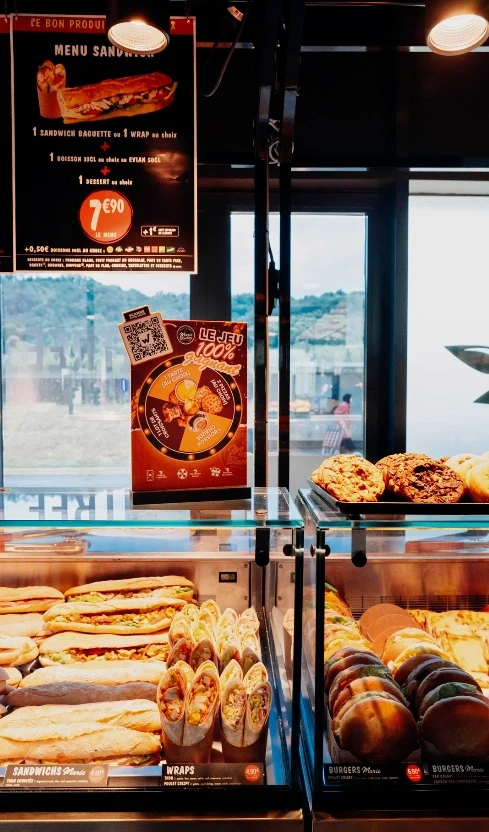 Vitrine de sandwichs et burgers de Marie Blachère avec le flyer du jeu concours posé dessus