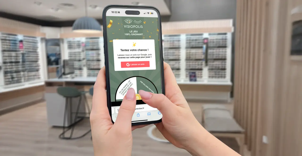 Smartphone en main affichant la roue à cadeaux du jeu concours Visiopolis dans le magasin d'optique