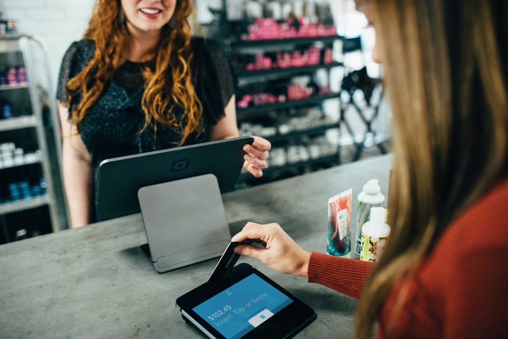 Commerçante encaissant une cliente sur sa caisse tablette en boutique