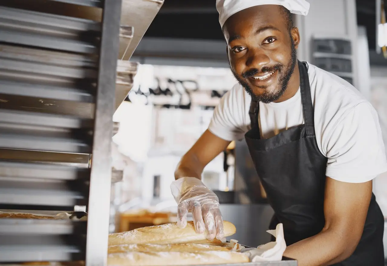 Boulanger souriant rangeant des baguettes fraîches dans sa boulangerie